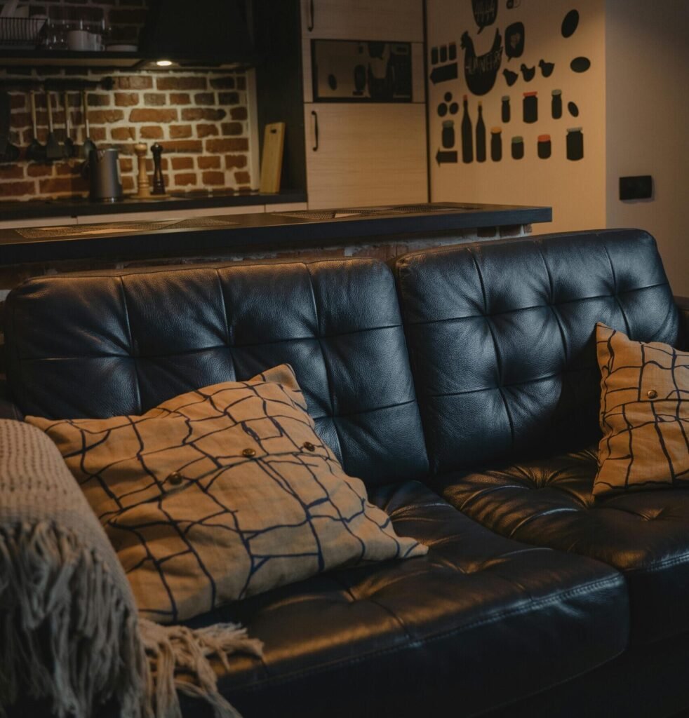 Simple Cozy Apartment Decor Ideas to Create a Warm and Beautiful Home A cozy leather couch adorned with throw pillows in a modern industrial interior setting.