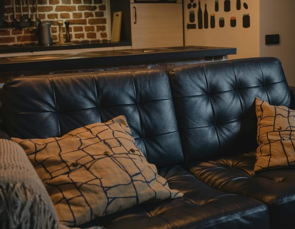 A cozy leather couch adorned with throw pillows in a modern industrial interior setting.