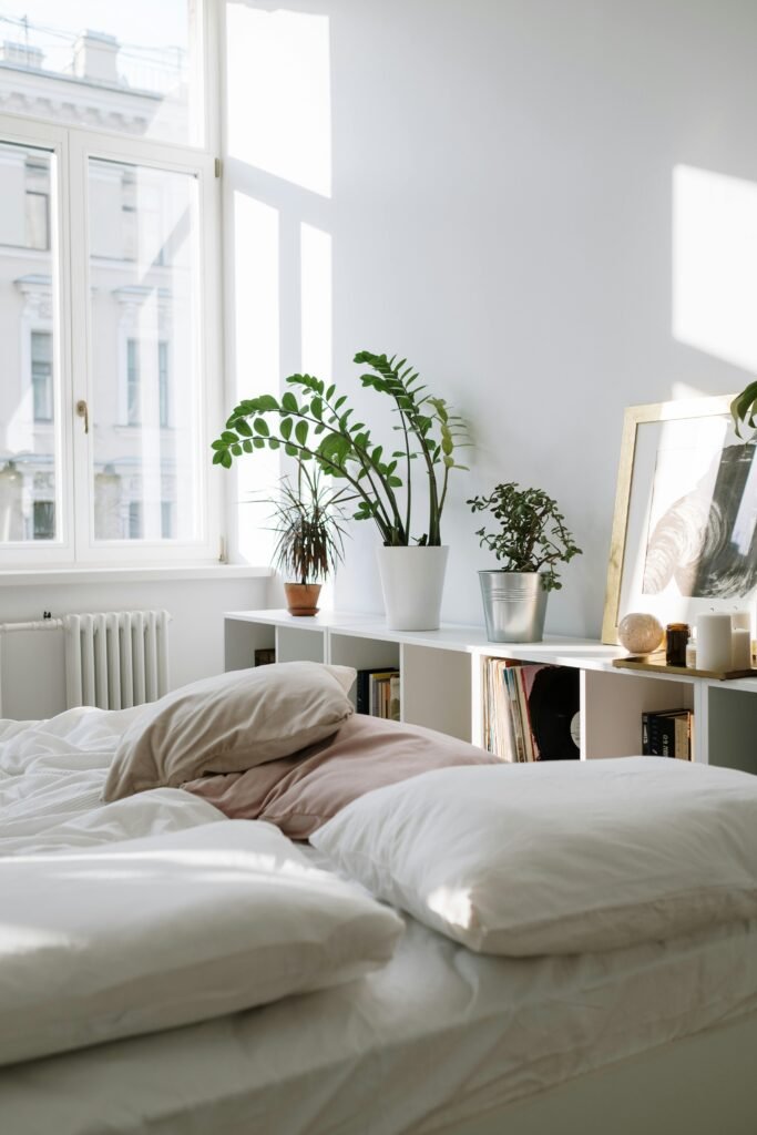 Bright and airy minimalist bedroom interior design with houseplants and natural light.