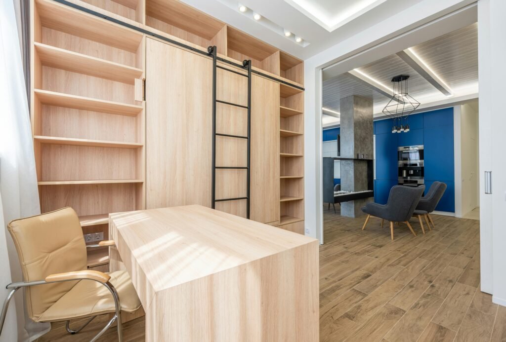 Bright and spacious home office with wooden furniture and shelving in a modern apartment.