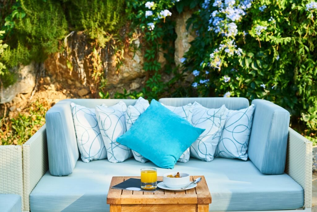 Inviting outdoor patio with a cozy sofa, cushions, and a refreshing drink on a wooden table.