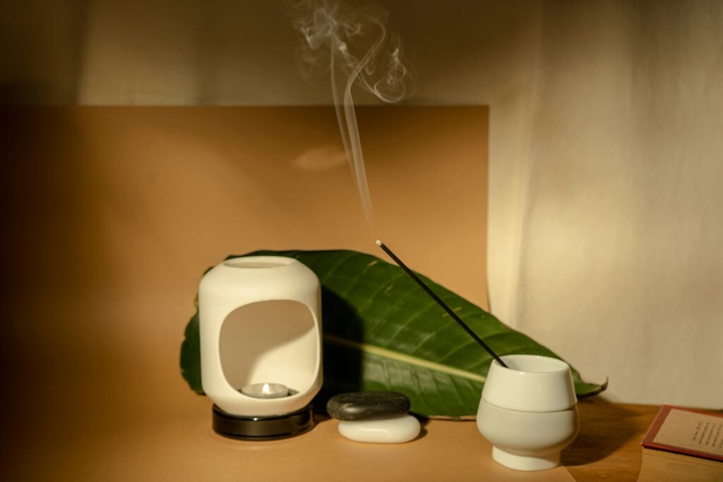 Minimalist aromatherapy scene featuring incense, tealight, and ceramic decor for a calming ambiance.